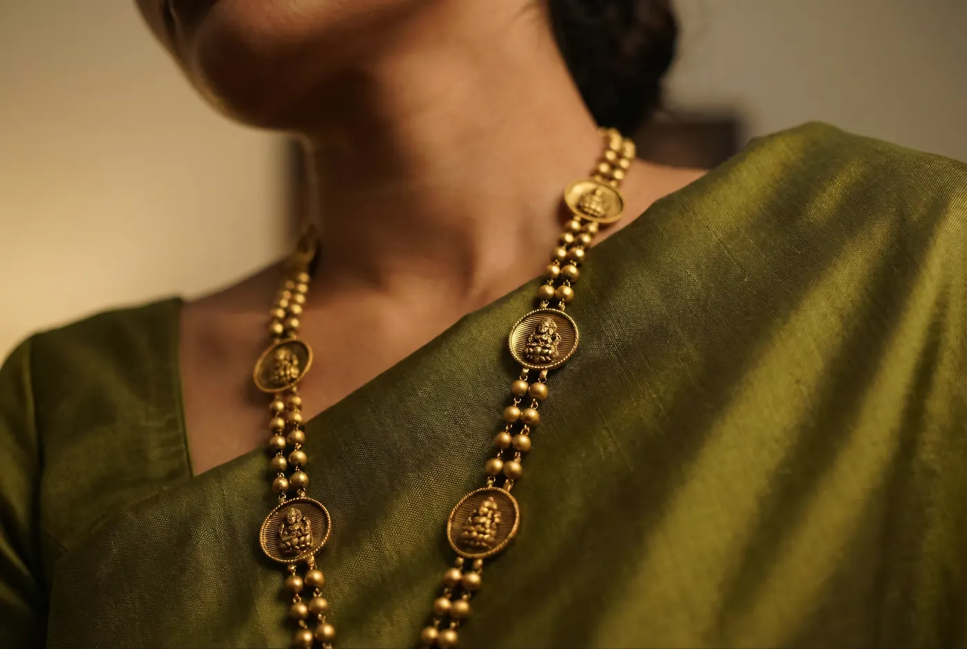 Temple gold necklace draped on olive silk, jewellery detail